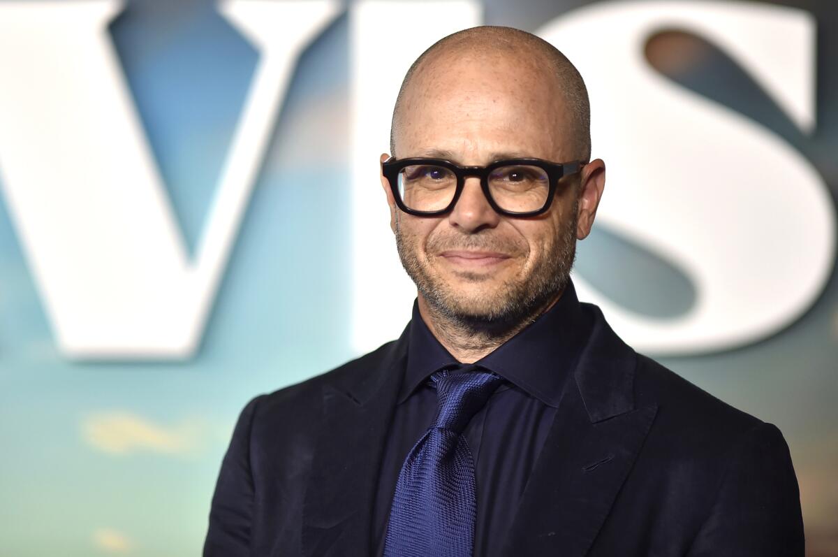 Damon Lindelof smiles in a black outfit with a blue tie.