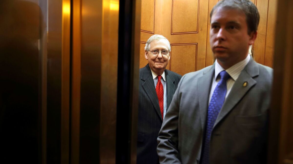 Senate Majority Leader Mitch McConnell of Ky., center, smiles as he takes an elevator after meeting with President Donald Trump and Senate Republicans on Nov. 28 in Washington.