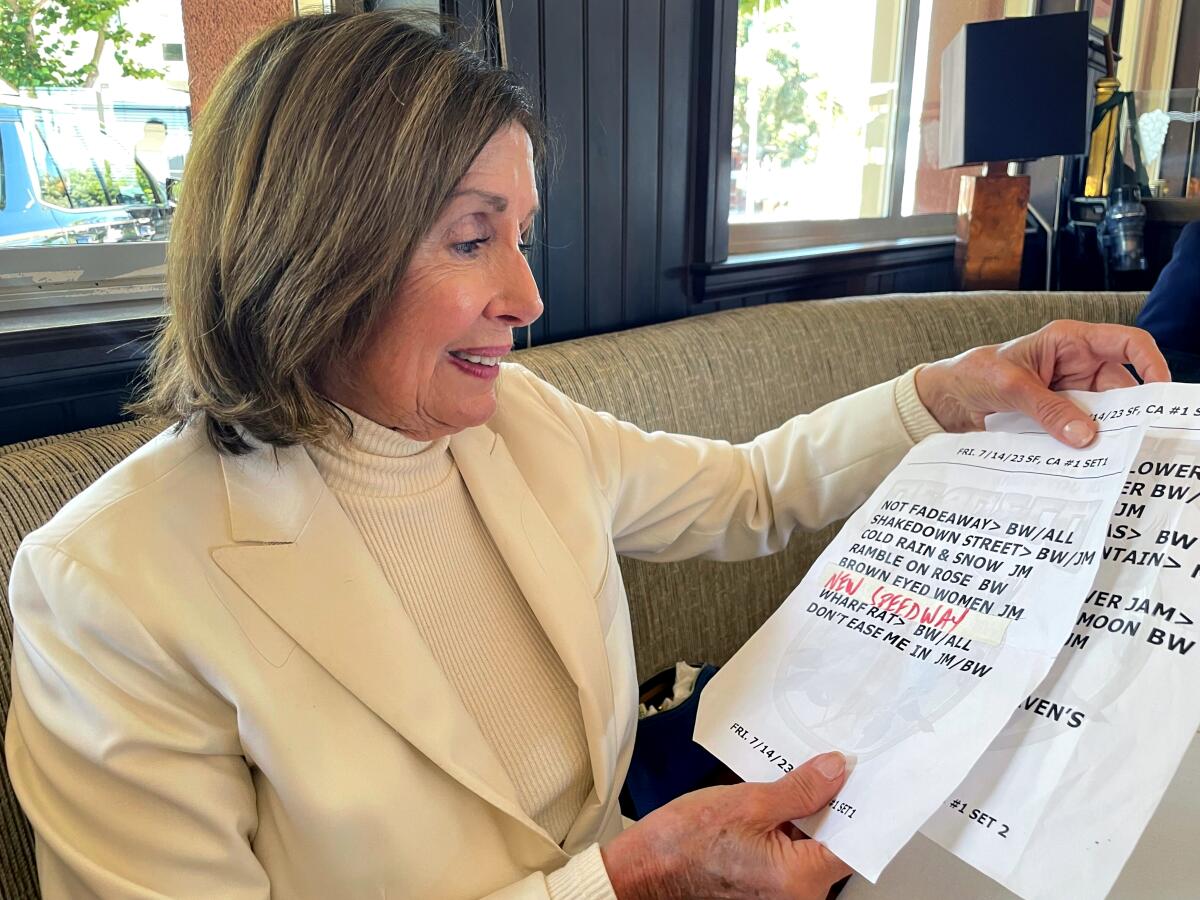 Nancy Pelosi holding a set list of the band Dead & Co.