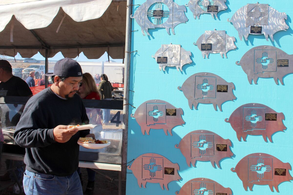 An eater holds plates of carne adovada and enchiladas at the World's Largest Matanza, an all-day festival celebrating New Mexico's hog-slaughtering traditions.