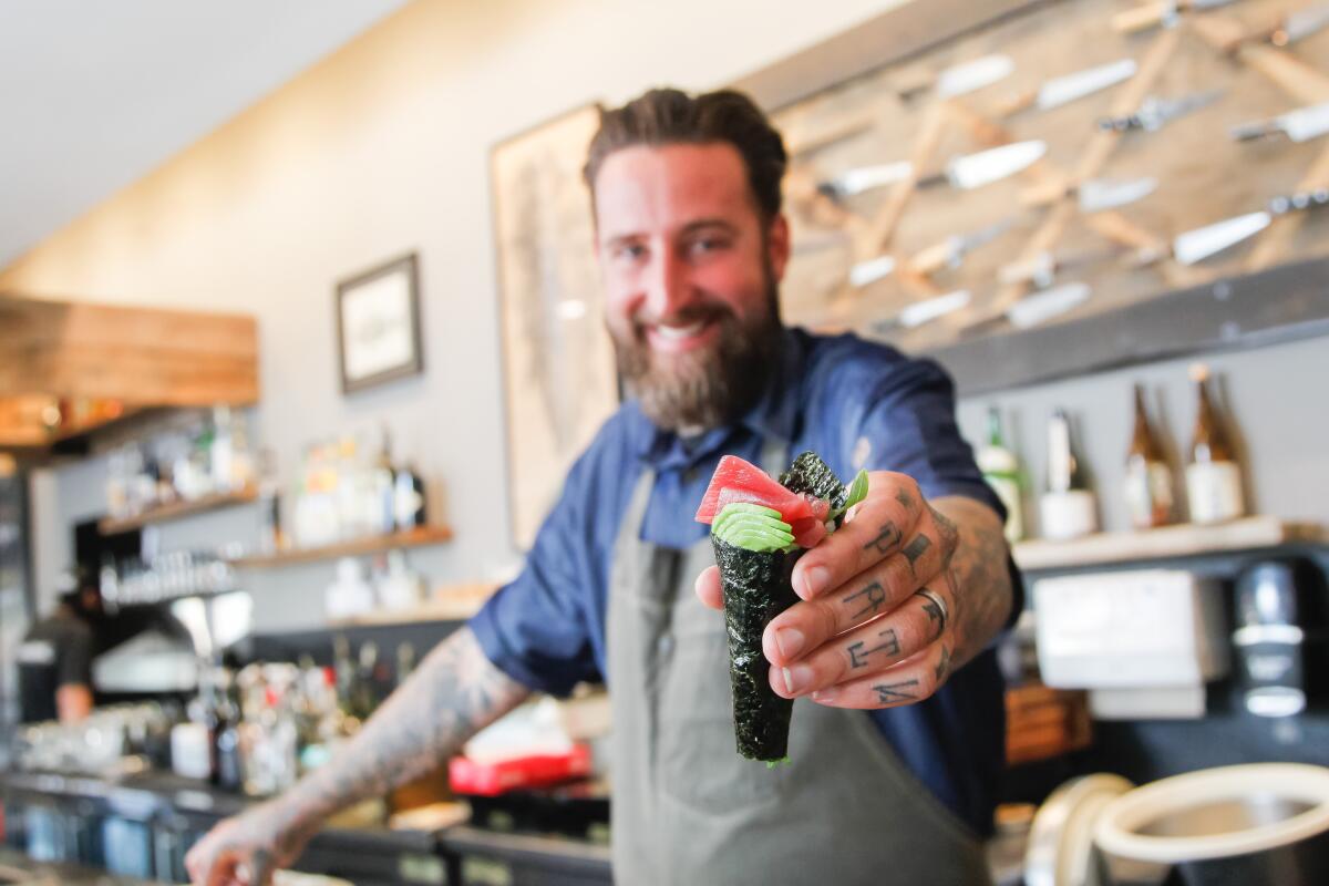 Chef Rob Ruiz displays a sushi hand roll like the ones he plans to serve at The Hold Fast, a booth serving fresh-caught San Diego seafood that will open this fall in Liberty Public Market at Liberty Station.