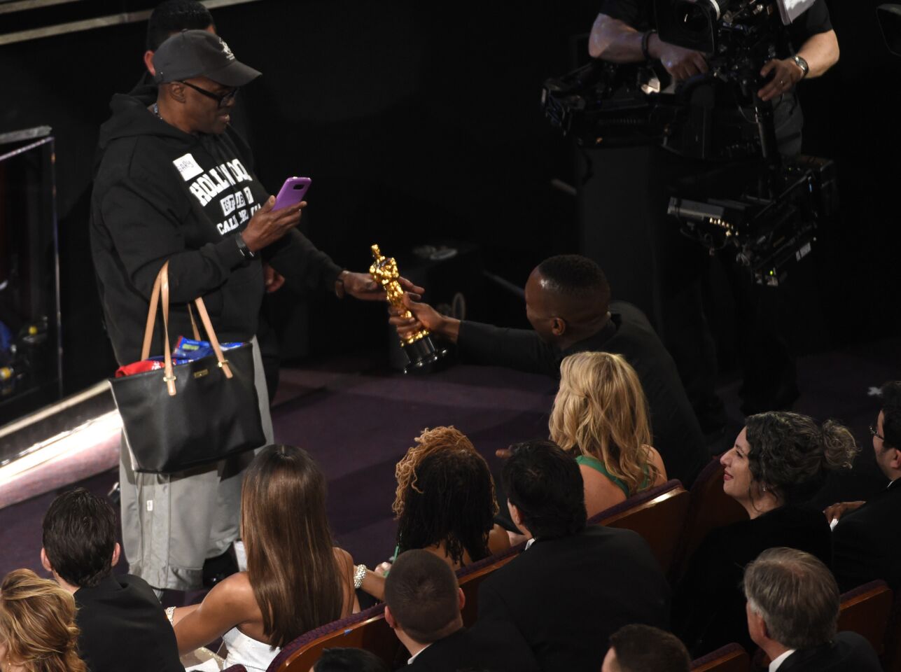 Mahershala Ali, right, hands his Oscar to a tourist named Gary who was brought into the theater with others as a surprise.