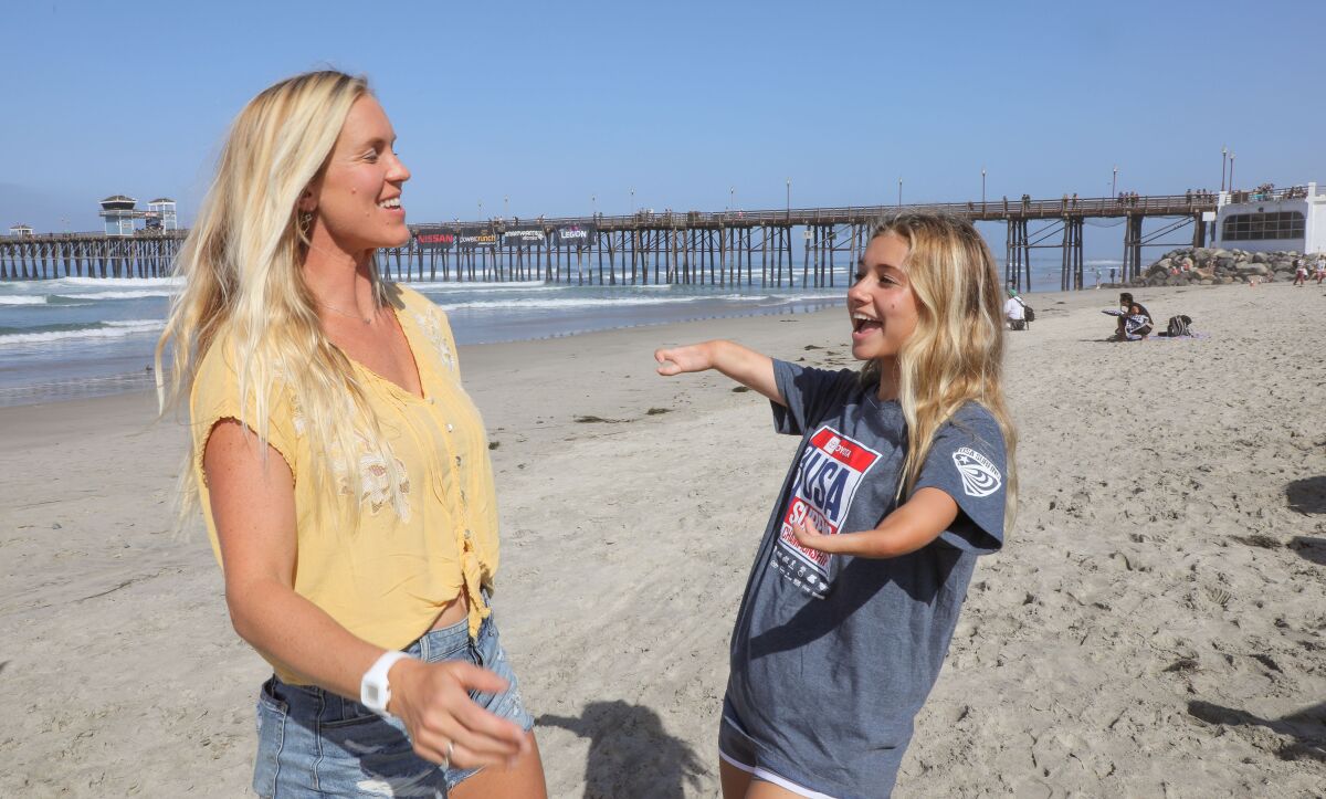 At the Super Girl Surf Pro contest at the Oceanside Pier, pro surfer Bethany Hamilton, of Hawaii, at left, who lost her left arm in a shark attack, chats with surfer Liv Stone, 16, of Carlsbad, at right, who was born with a congenital deformity of her arms  