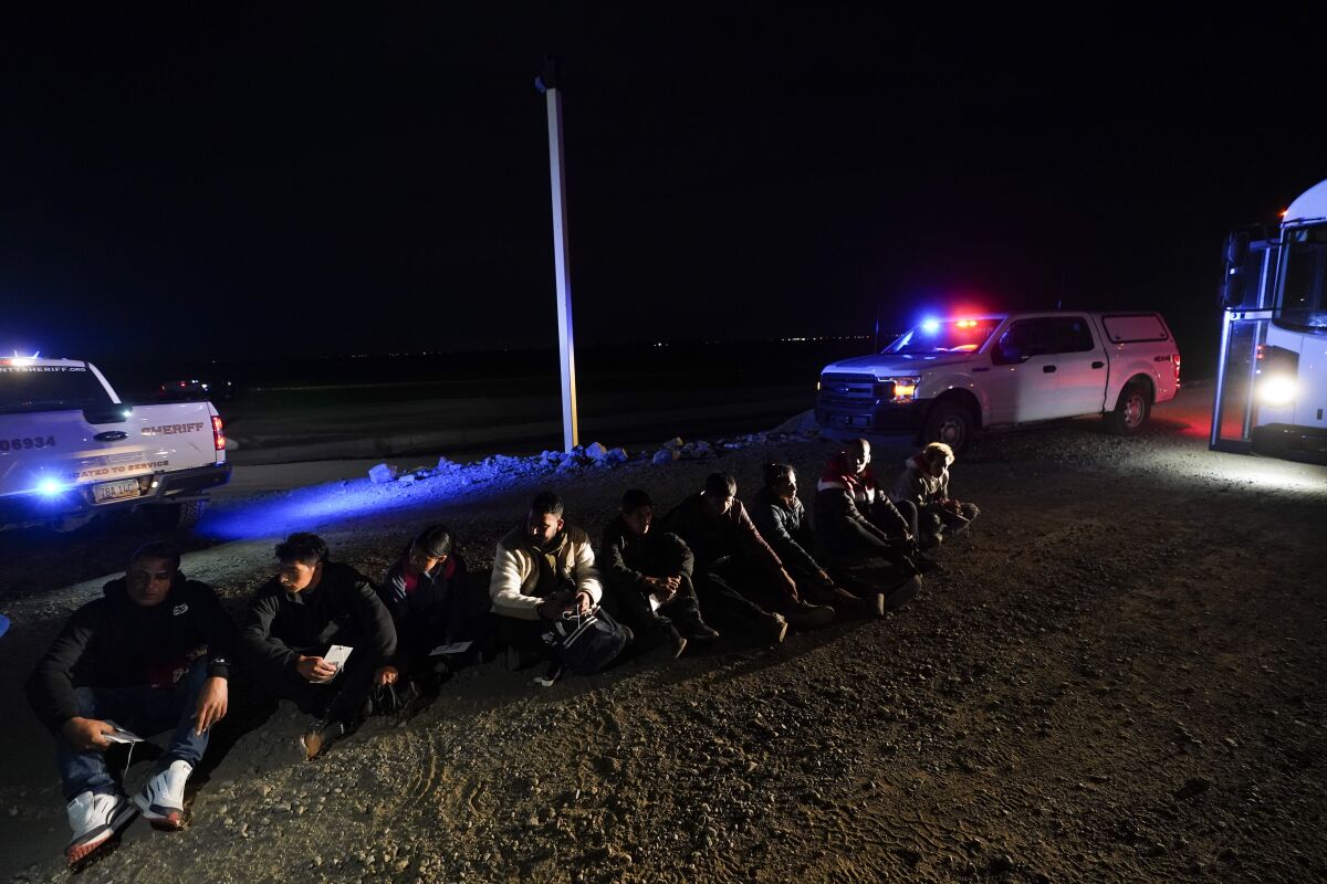  Migrants sitting on the ground at night.