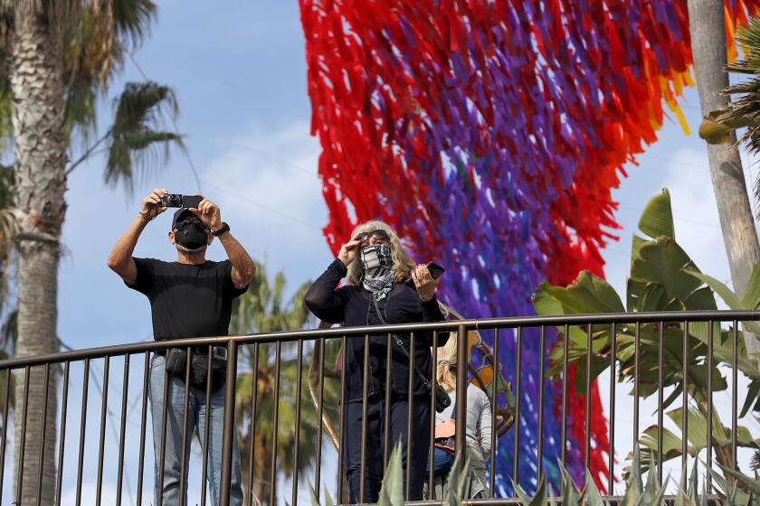 A couple take pictures of this year's Laguna Beach Art Museum's Art and Nature exhibit, Patrick Shearn's Skynet, suspended along the coastline path from Las Brisas to Main Beach.