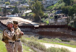 A pair of U.S. soldiers look towards Tijuana that rests behind the border wall with new concertina wire near San Ysidro.