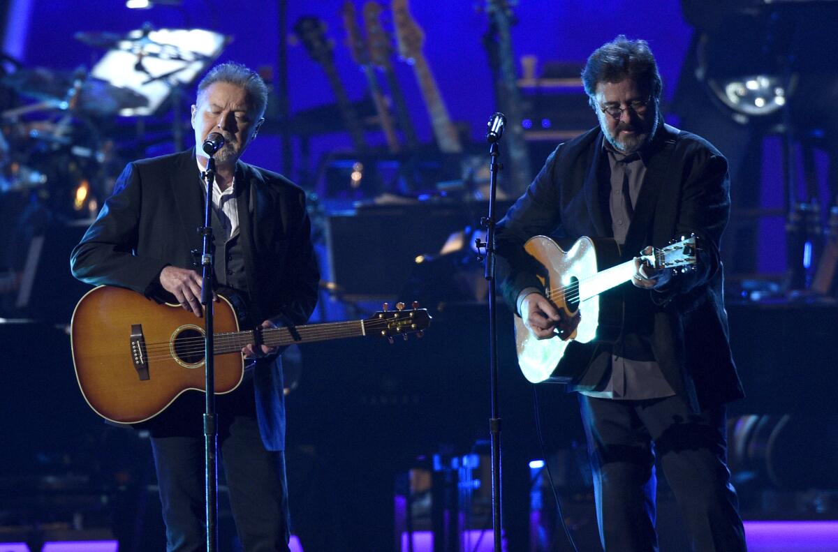 Don Henley, left, and Vince Gill of the Eagles play guitars onstage
