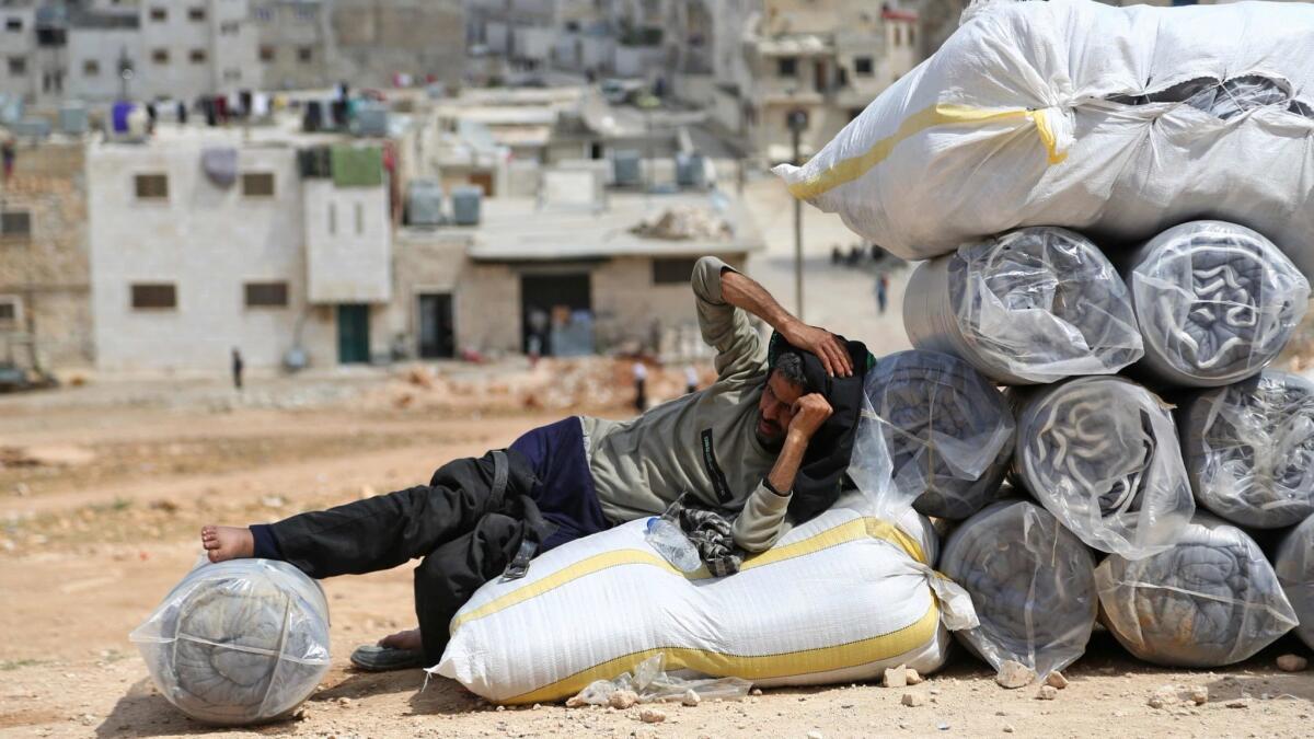 A Syrian man who was evacuated from the eastern Ghouta enclave of Duma rests on bags as he waits to find shelter on April 12, 2018.