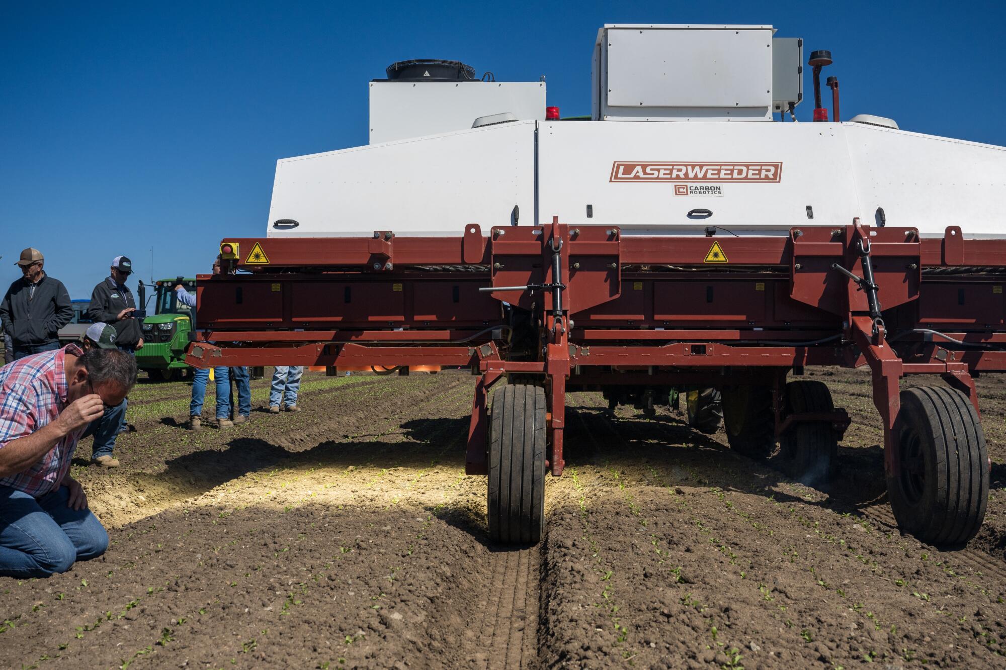 A large agricultural device shines bright light on a field.