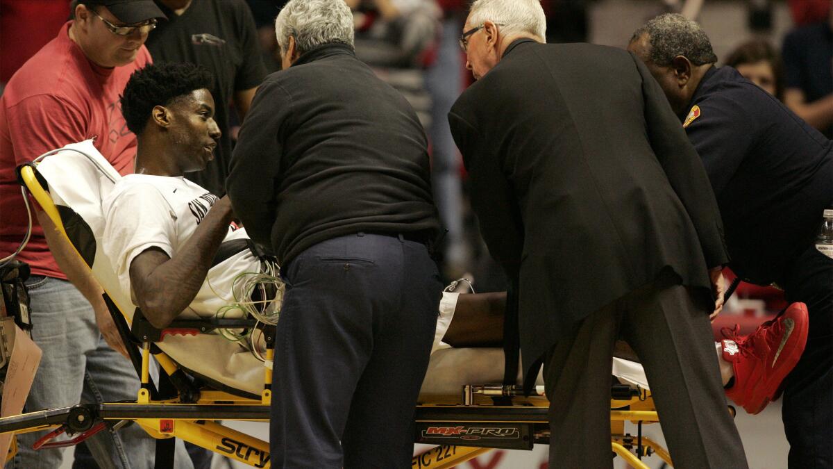 San Diego State's Dwayne Polee is wheeled off on a stretcher while speaking to Coach Steve Fisher, right, during a game against UC Riverside on Monday night.