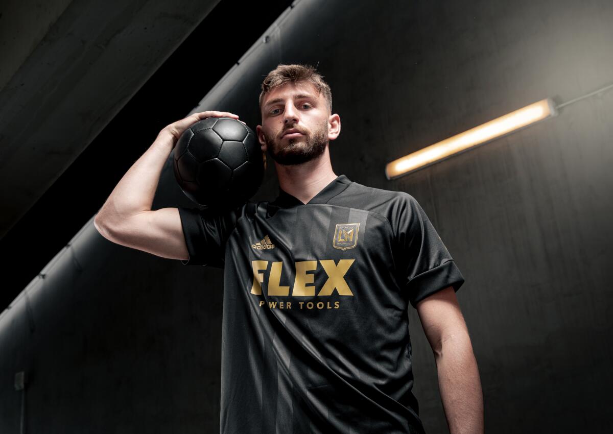 LAFC player Tristan Blackmon shows off the team's new jersey, which is black and says "Flex power tools" in gold lettering.