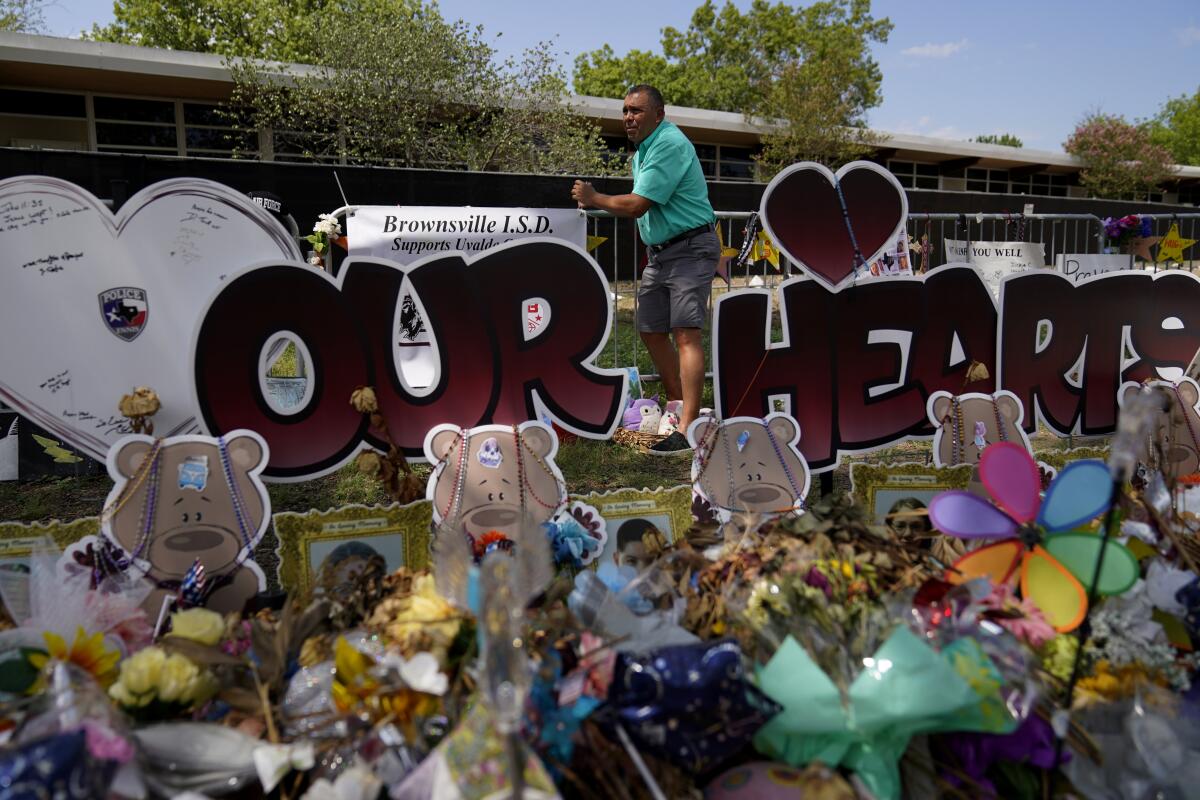 Brownsville school superintendent Dr. Rene Gutierrez adds a banner to a make-shift memorial that honor the victims of the school shootings at Robb Elementary, Tuesday, July 12, 2022, in Uvalde, Texas. (AP Photo/Eric Gay)