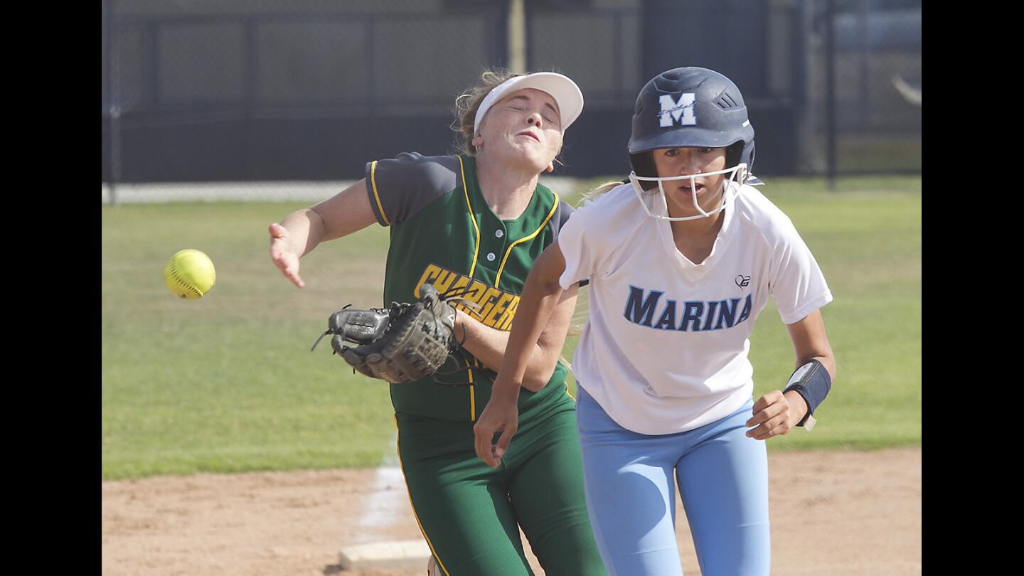Marina's Nicole Logrecco, right, heads for home as Edison's Hannah Matthews tries to make a catch in girls varsity softball action at Marina High on Tuesday.