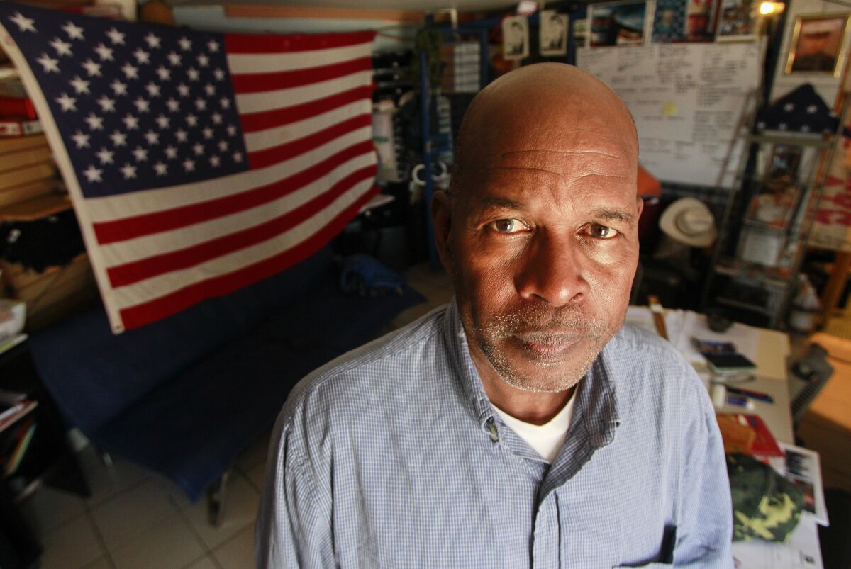 Roman Sabal stands in front of a U.S. flag at the Deported Veterans Support House