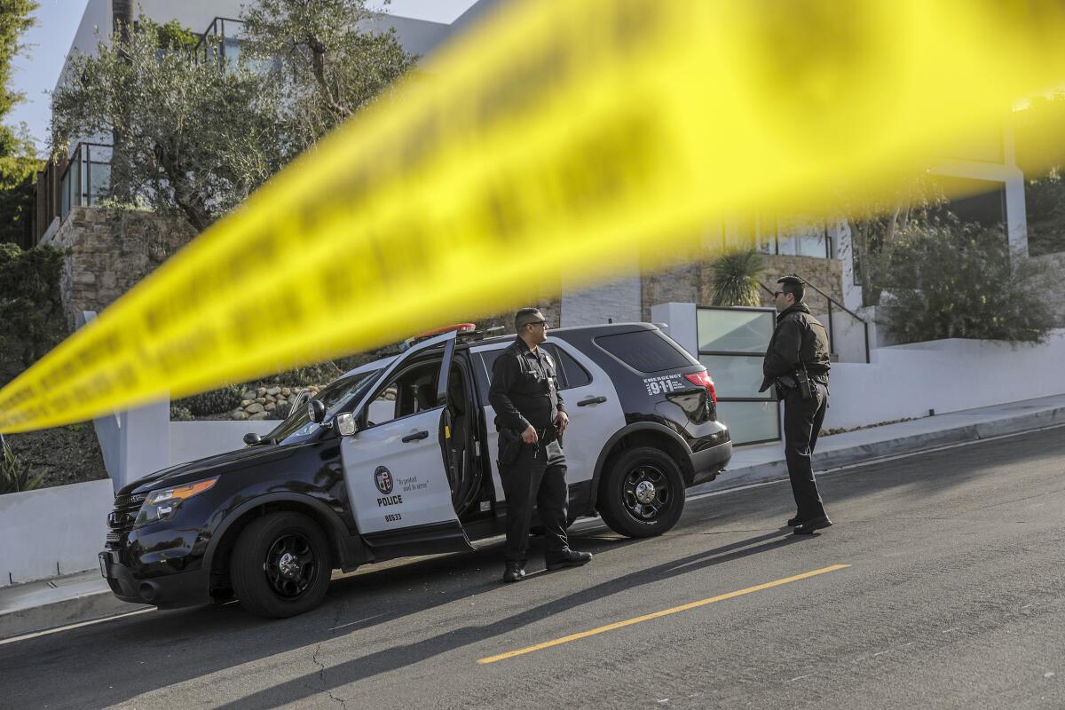 LAPD officers close a road leading to the Hollywood Hills home where rapper Pop Smoke was fatally shot Wednesday morning.