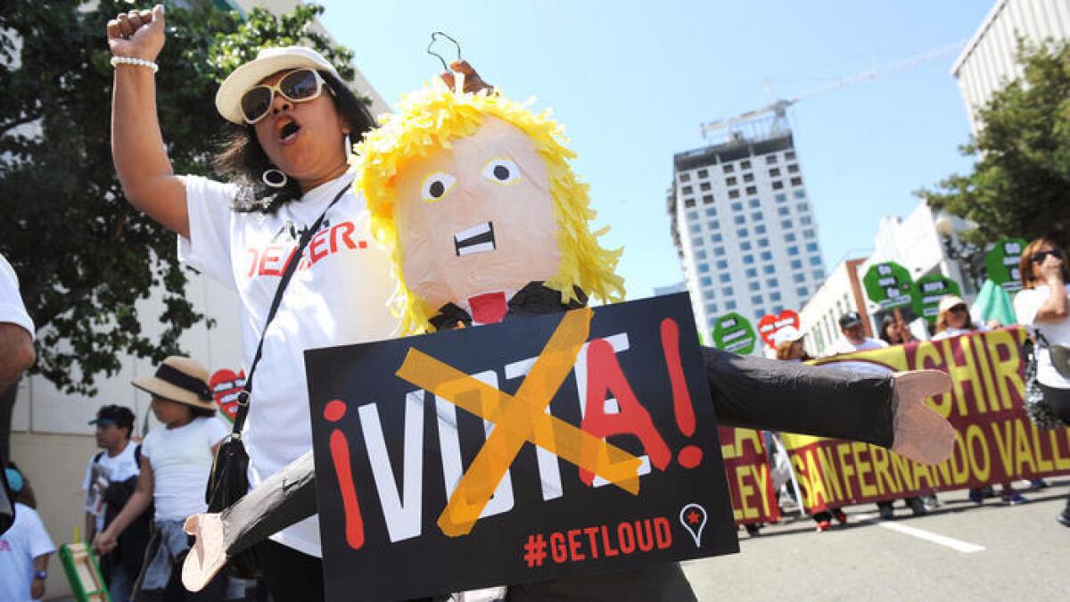 Emma Torres de Van Nuys sostiene una piñata con la figura de Donald Trump, durante una marcha en el centro de Los Angeles.