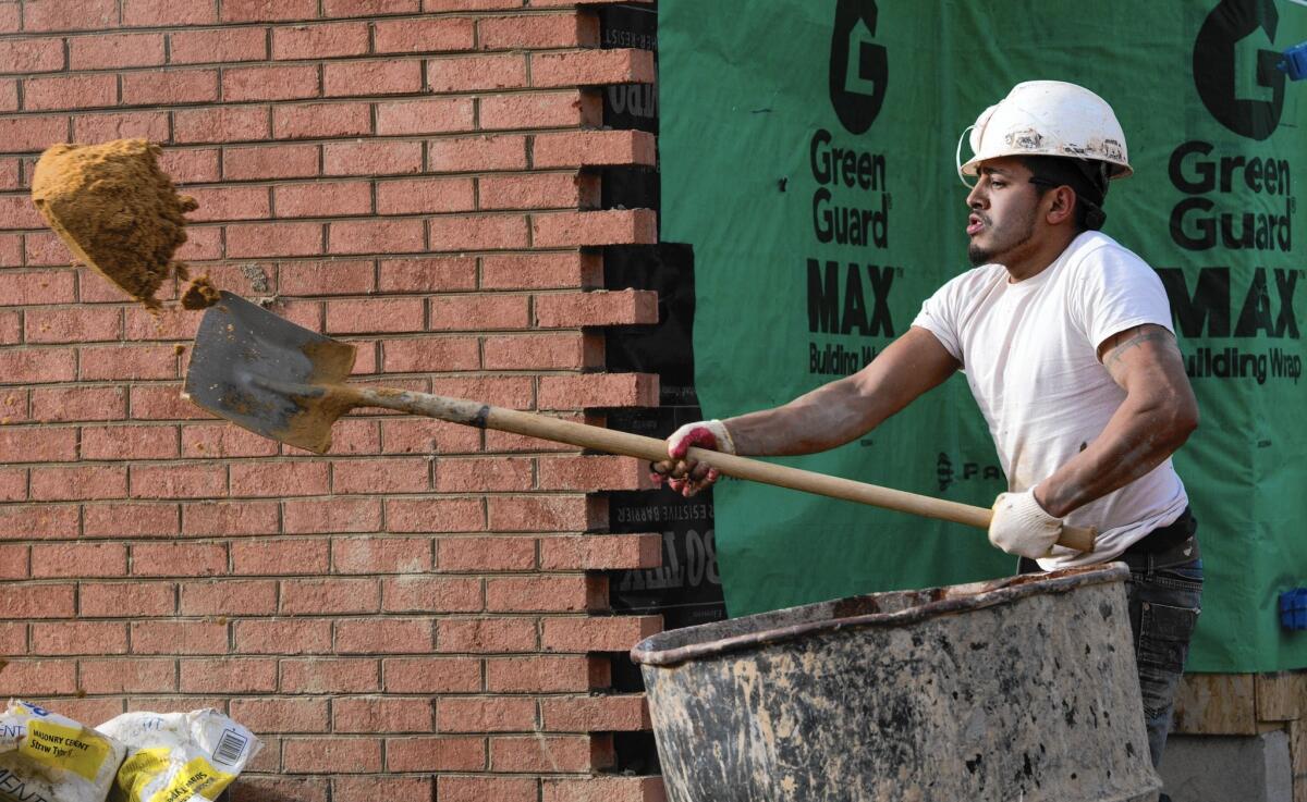 The FHA will drop its annual premiums on new mortgages to 0.85% from 1.35% of the total loan amount. Above, a worker prepares a load of cement in January to cover a new home in Ashburn, Va., in bricks.
