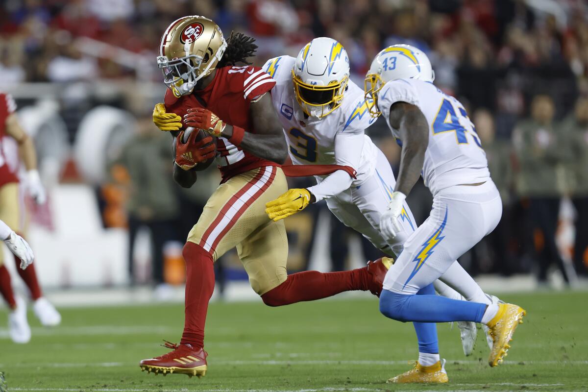 49ers wide receiver Brandon Aiyuk, left, is tackled by Chargers safety Derwin James Jr. and cornerback Michael Davis.