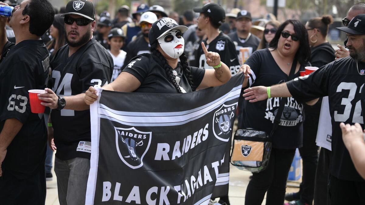 A Raiders fan poses with a flag at the Coliseum.