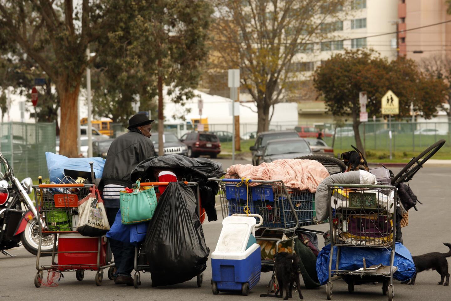 Ricky Riller carries his belongings and dogs in shopping carts before sanitation workers sweep the homeless encampments in the Manchester Square neighborhood in Los Angeles.