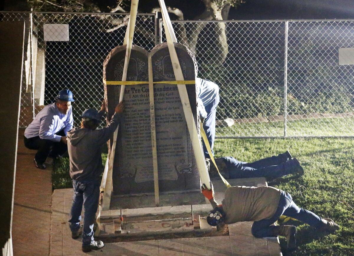 Workers remove the Ten Commandments monument from its base on the grounds of the state Capitol in Oklahoma City.