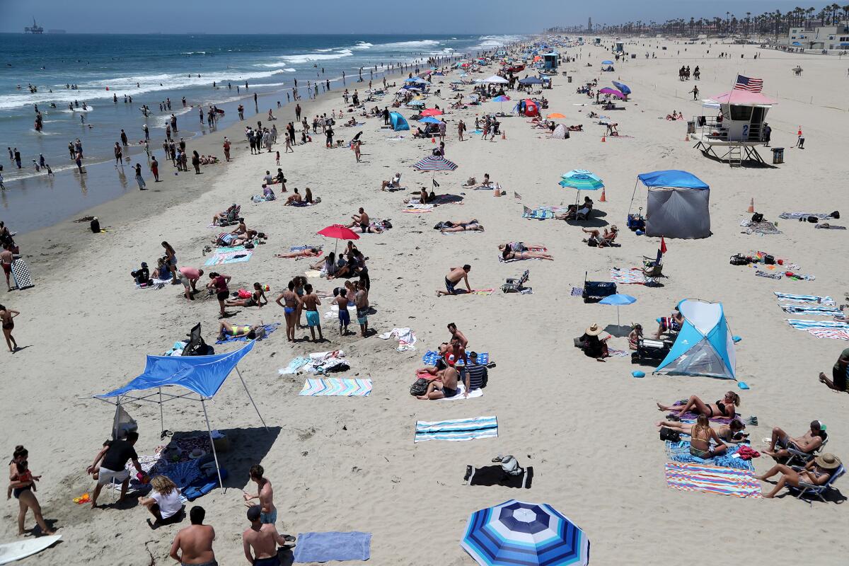 Beach-goers enjoy the sunshine and ocean water on the north side of the pier on Saturday in Huntington Beach