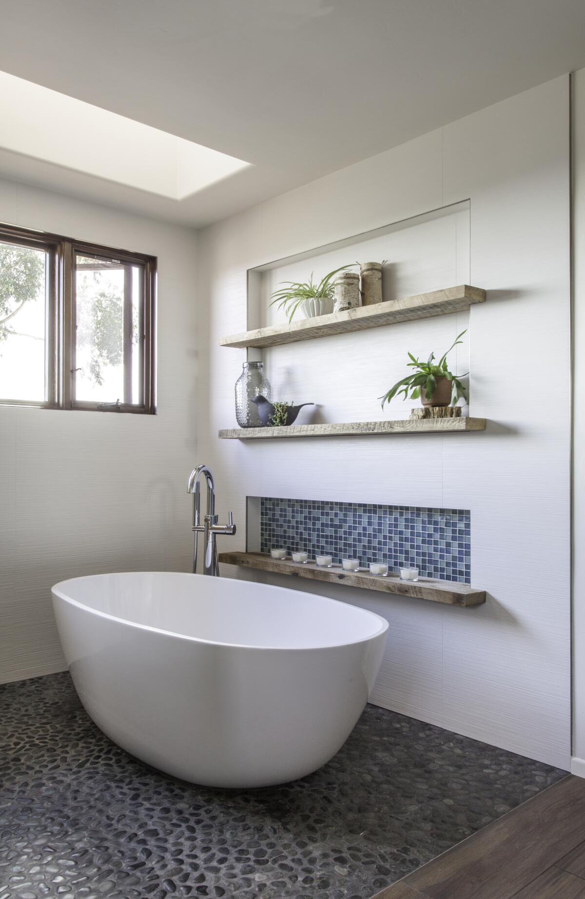 Plants are placed on horizontal shelves alongside the new freestanding tub in the remodeled primary bathroom.