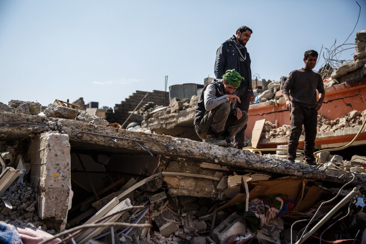 Neighbors and volunteers watch as corpses are pulled out of the rubble of a home destroyed by reported coalition air strikes in the al-Jadida neighborhood of Mosul, Nineveh Province. (Marcus Yam / Los Angeles Times)