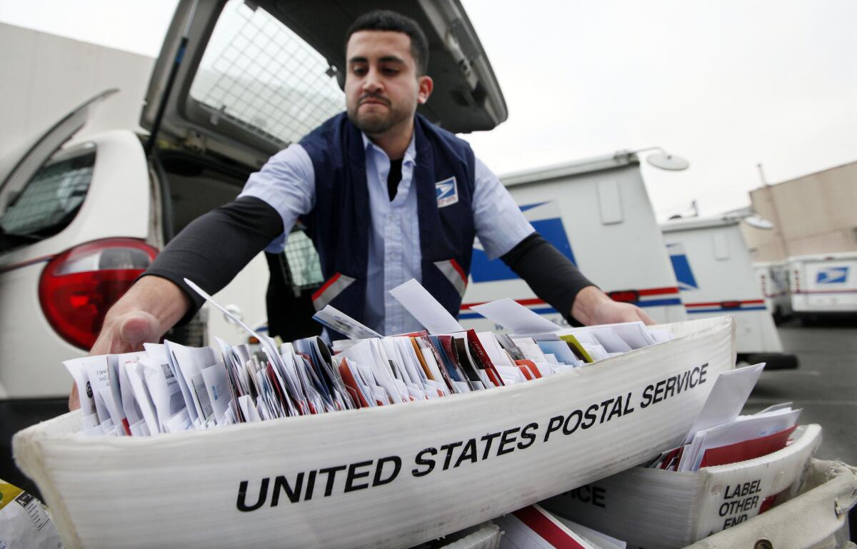 Letter carrier Felipe Raymundo moves a tray of mail to his truck to begin delivery Monday, Dec. 5, 2011, at a post office in Seattle.
