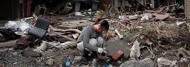 A woman looks through the rubble of her home in Kensennuma.