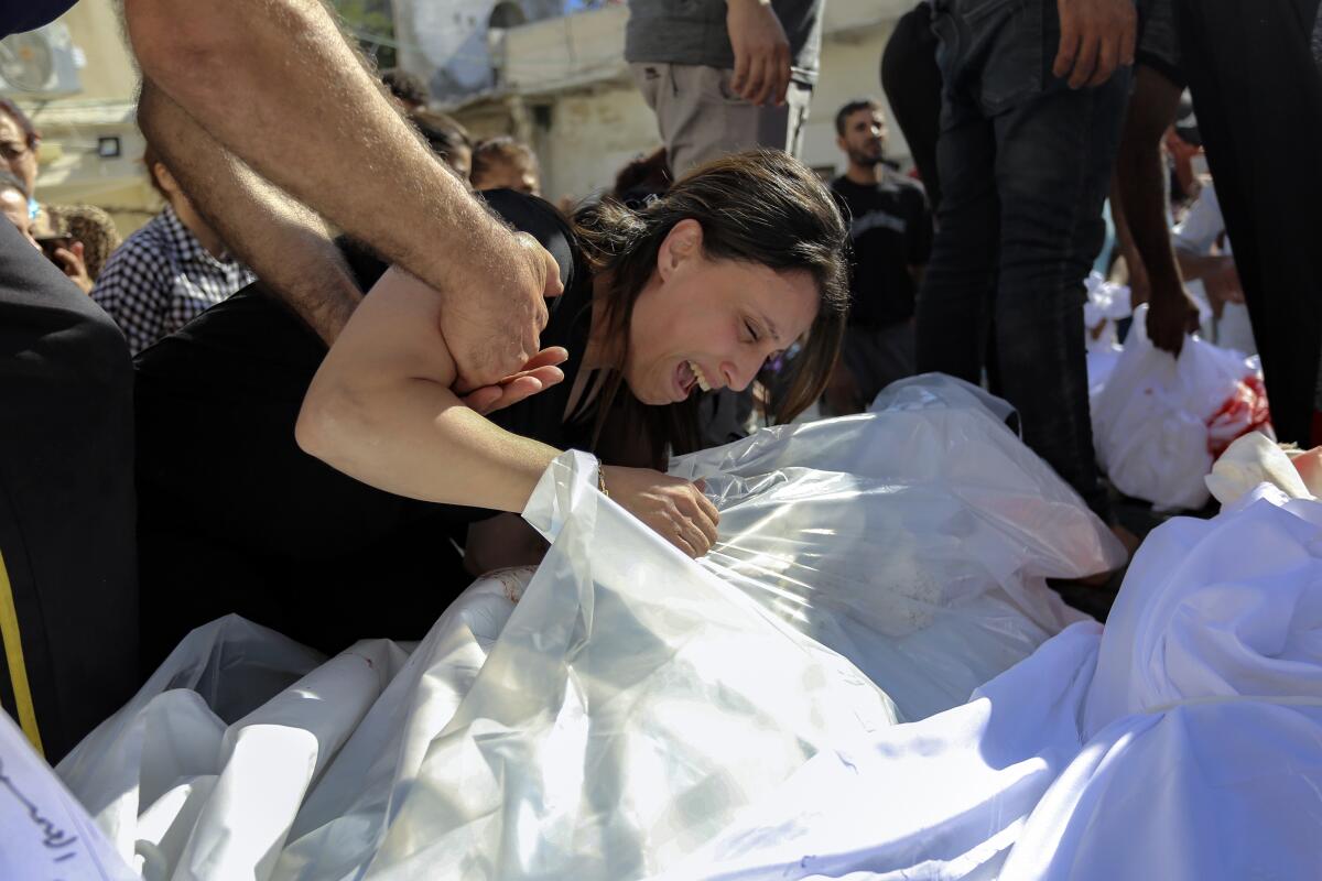 A Palestinian woman mourns over the bodies of her relatives who were killed in airstrikes that hit a Greek Orthodox church.