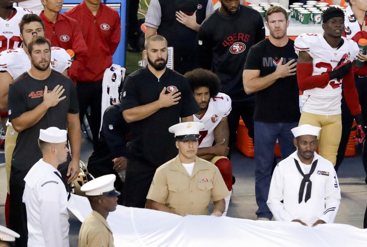 San Francisco 49ers quarterback Colin Kaepernick, center, refuses to stand during the national anthem before the team's NFL preseason football game against the San Diego Chargers on Thursday in San Diego.