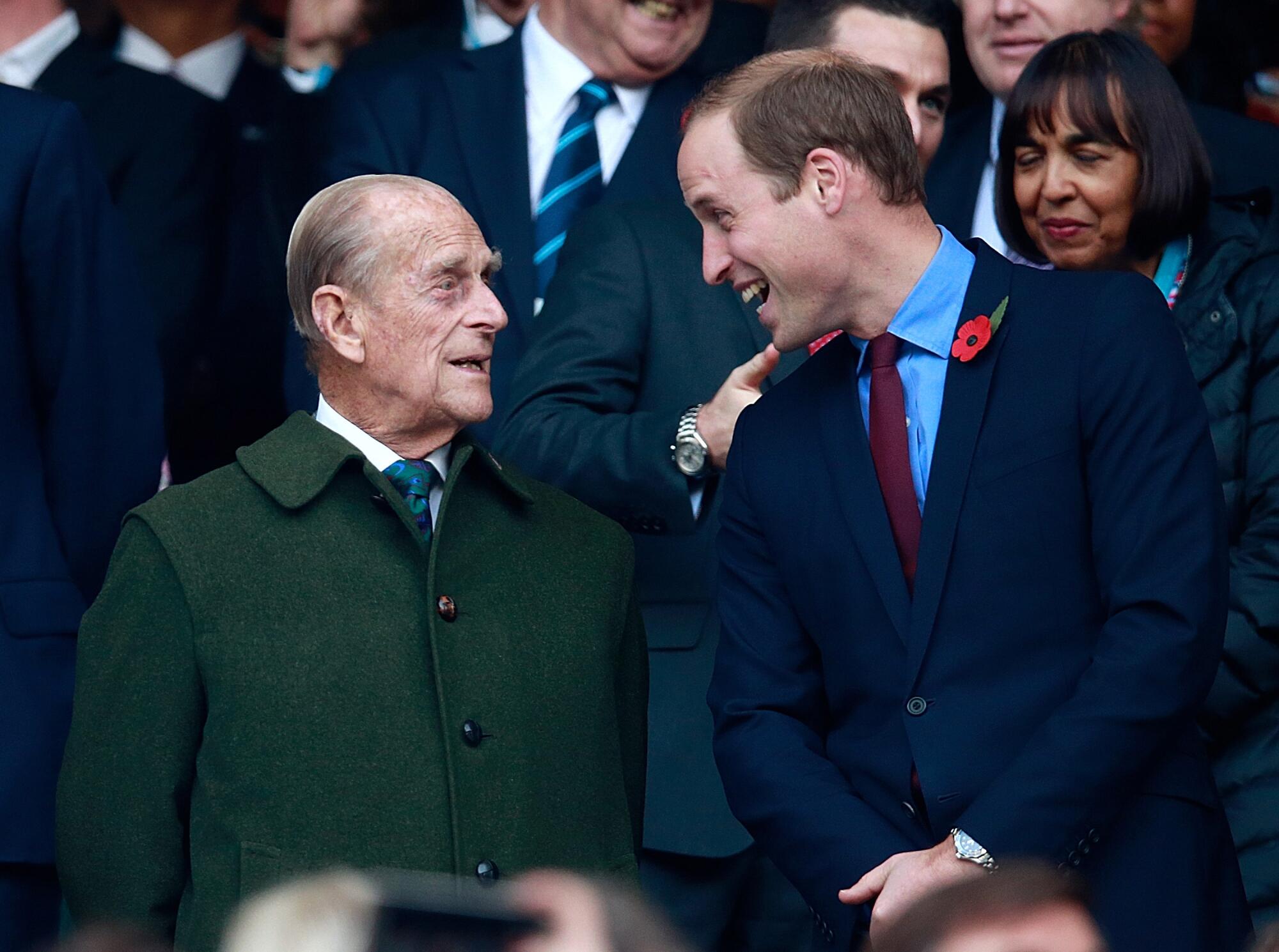 Prince Philip smiles and Prince William laughs at an outdoor event.