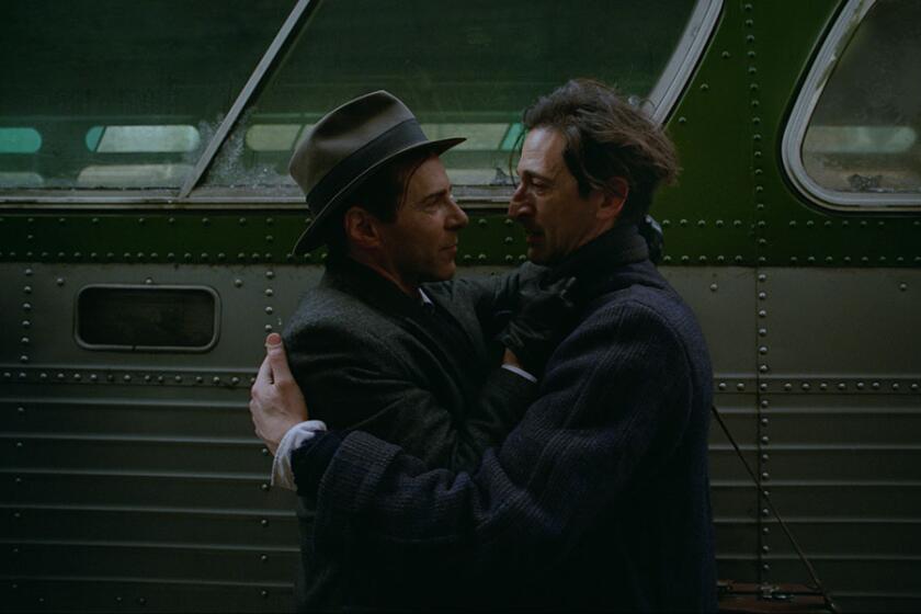 Two men embrace next to a bus.