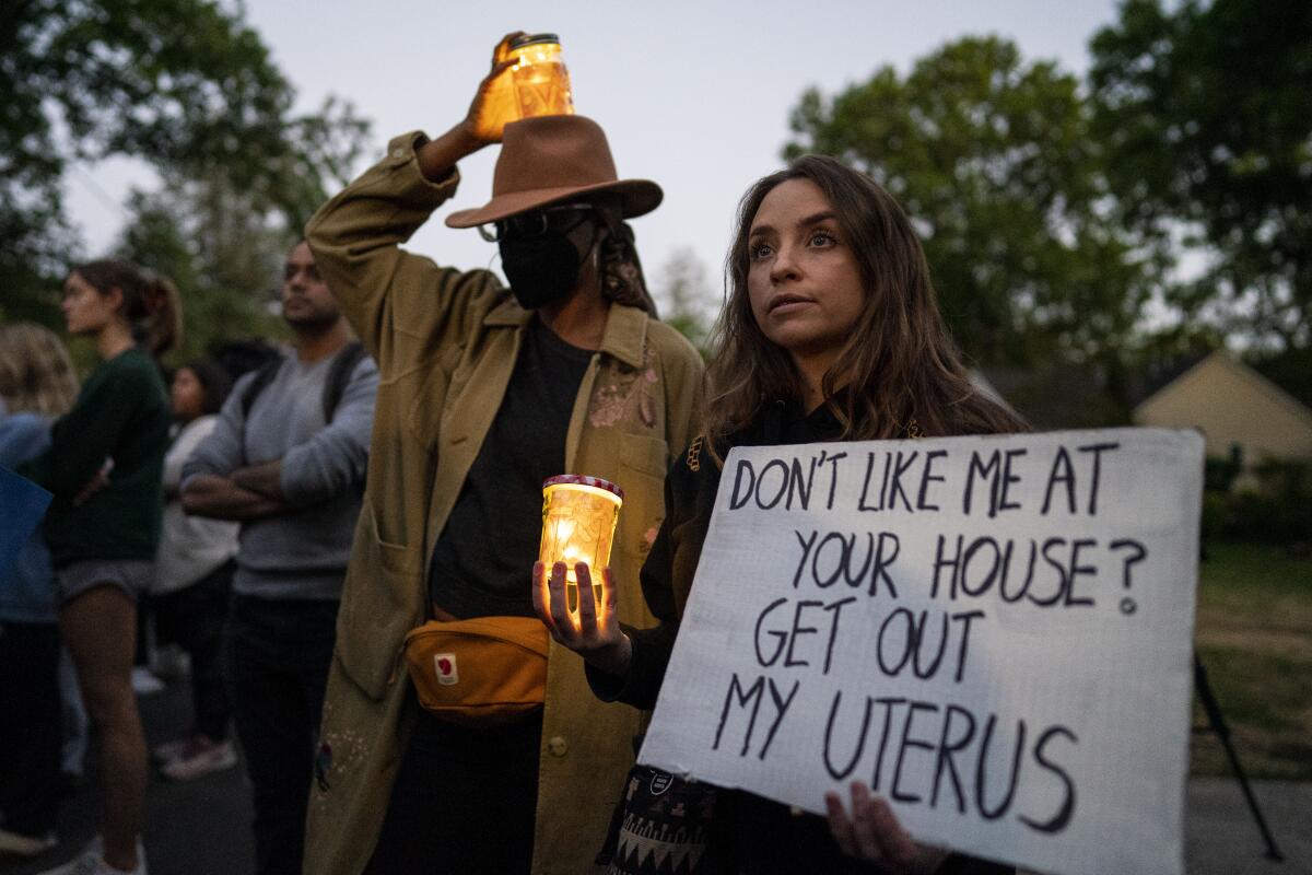 Abortion rights advocates hold candles and signs 