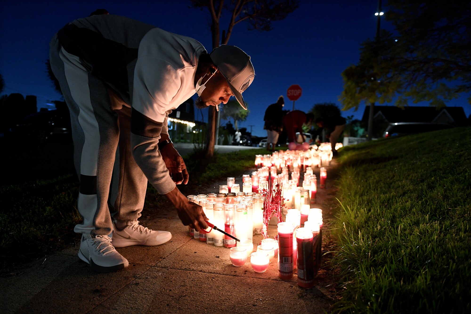 A man lights a candle on a sidewalk at night