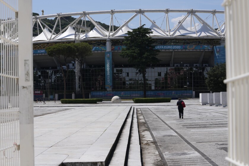 A man walks in front of Rome's Olympic stadium, Wednesday, June 9, 2021. The Euro 2020 gets underway on Friday June 11 and is being played in 11 host cities across 11 countries. (AP Photo/Alessandra Tarantino)