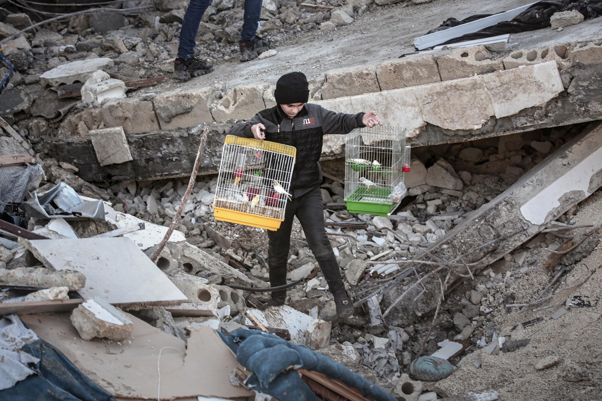 A child carries two bird cages with birds that were rescued alive from rubble of a collapsed building