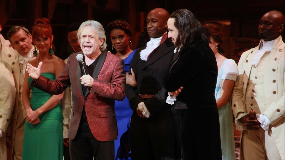 Luis Miranda, holding a microphone, onstage with Lin-Manuel Miranda and the rest of the "Hamilton" cast.