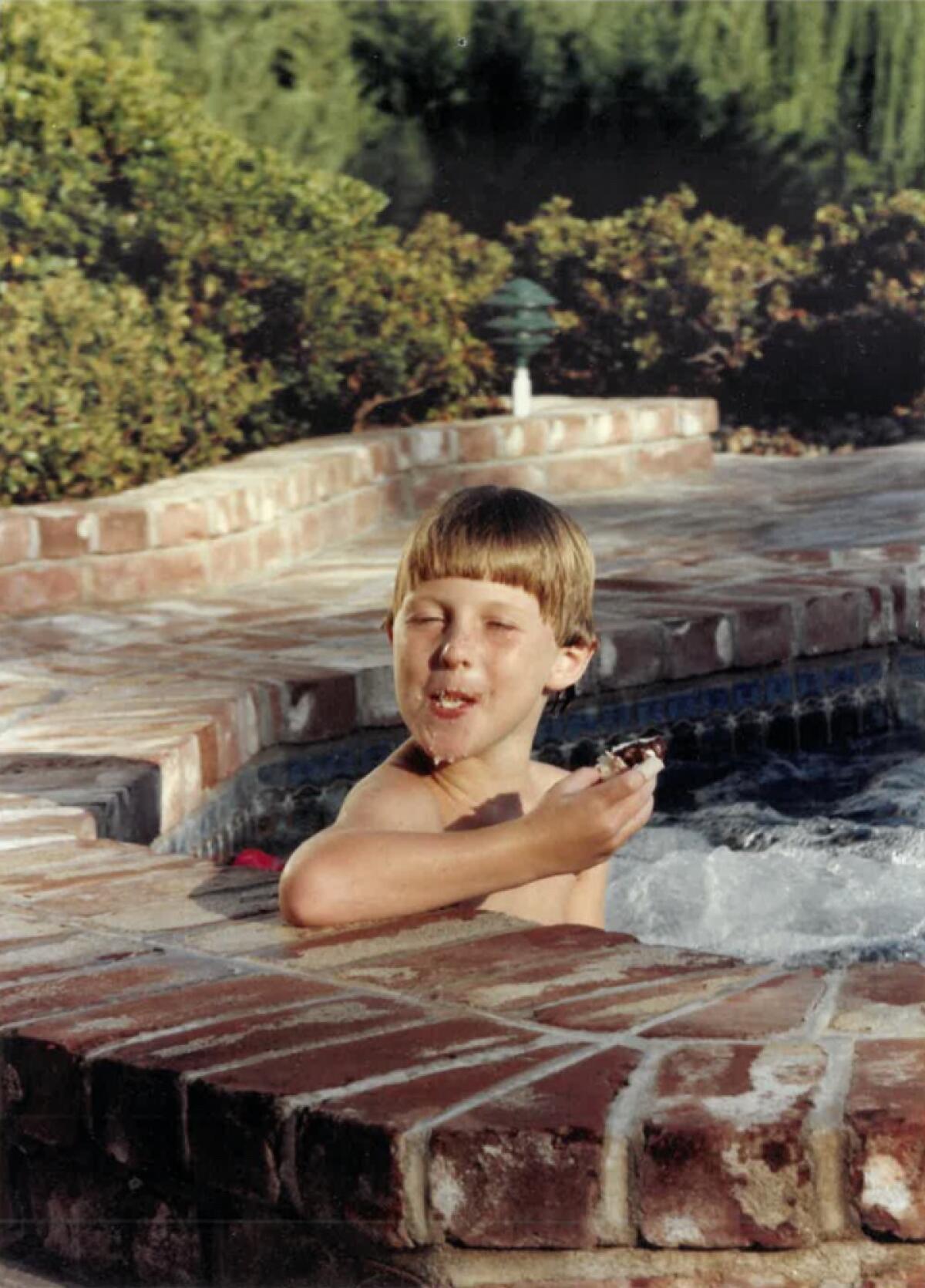 A child makes a silly face while sitting in a pool.