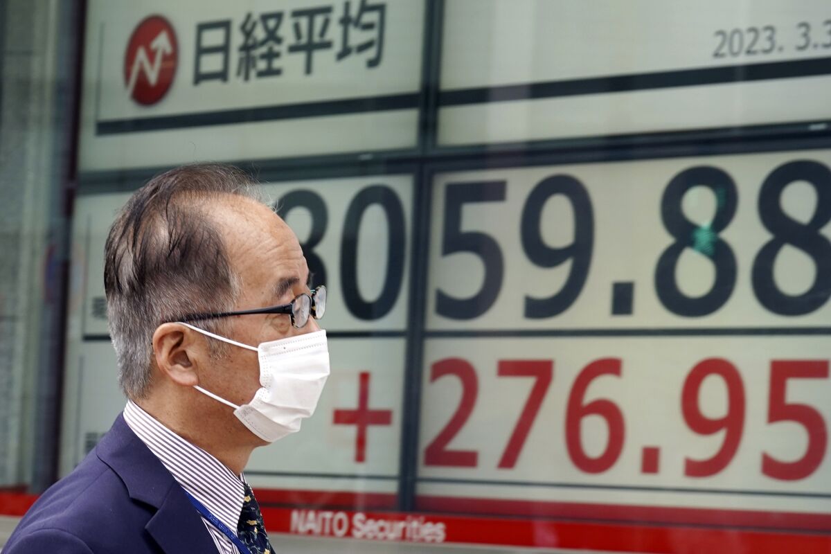 A person walks in front of an electronic stock board showing Japan's Nikkei 225 index at a securities firm Friday, March 31, 2023, in Tokyo. Asian stocks followed Wall Street higher Friday ahead of a United States inflation update that traders hope will prompt the Federal Reserve to ease plans for more interest rate hikes. (AP Photo/Eugene Hoshiko)