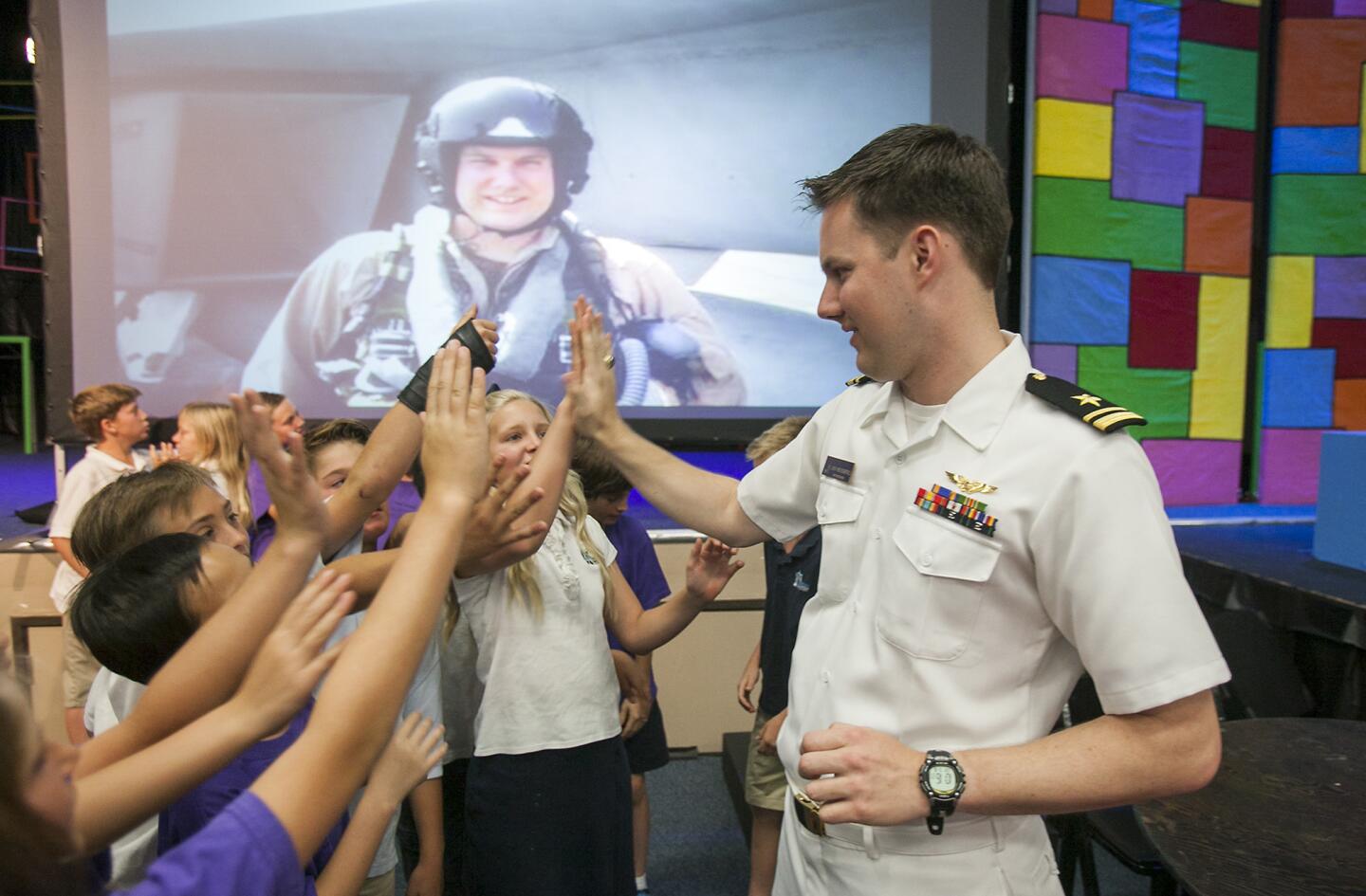 Lt. j. g. Jon Weissberg, a weapons system operator in the U.S. Navy, and alumni of Mariners Christian School, high fives students at the school on Friday, May 16. (Scott Smeltzer - Daily Pilot)