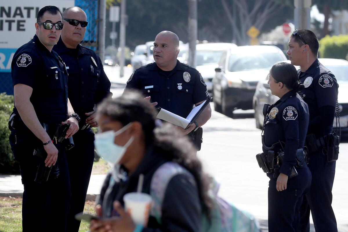 Police officers stand outside a school.