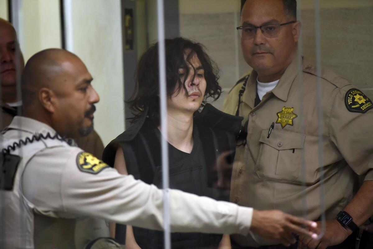 Law enforcement officers escorting a disheveled young man