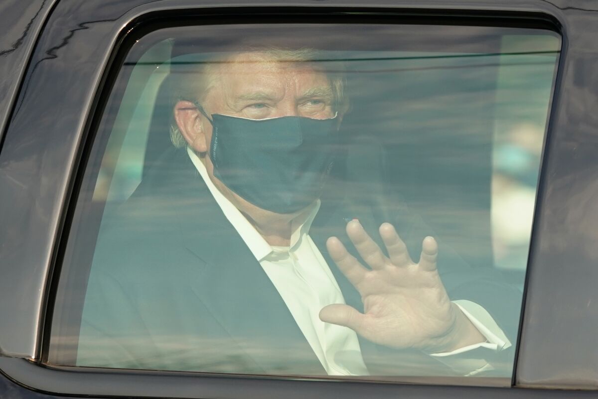 President Trump waves to supporters from a car.