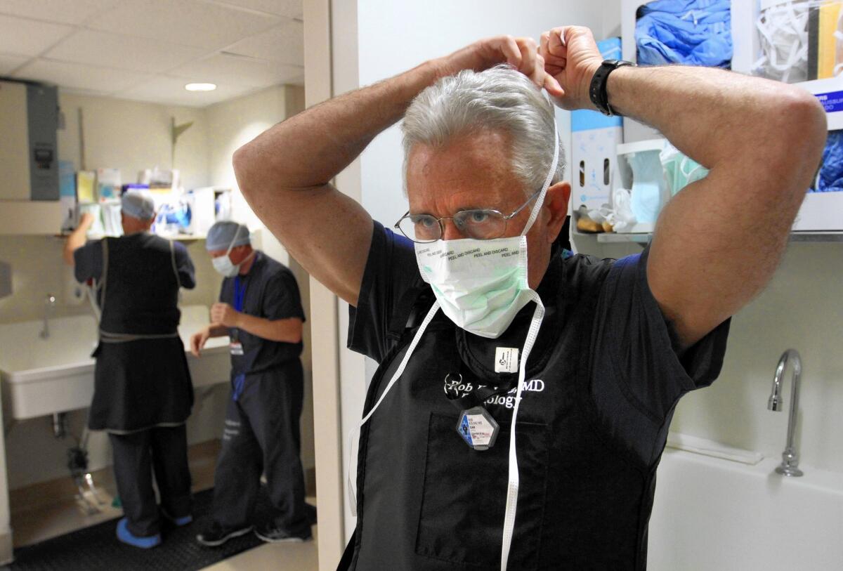 Dr. Robert Kolanz, right, dons a sterile mask at Providence Little Company of Mary Medical Center in Torrance, which earned an A grade for patient safety.
