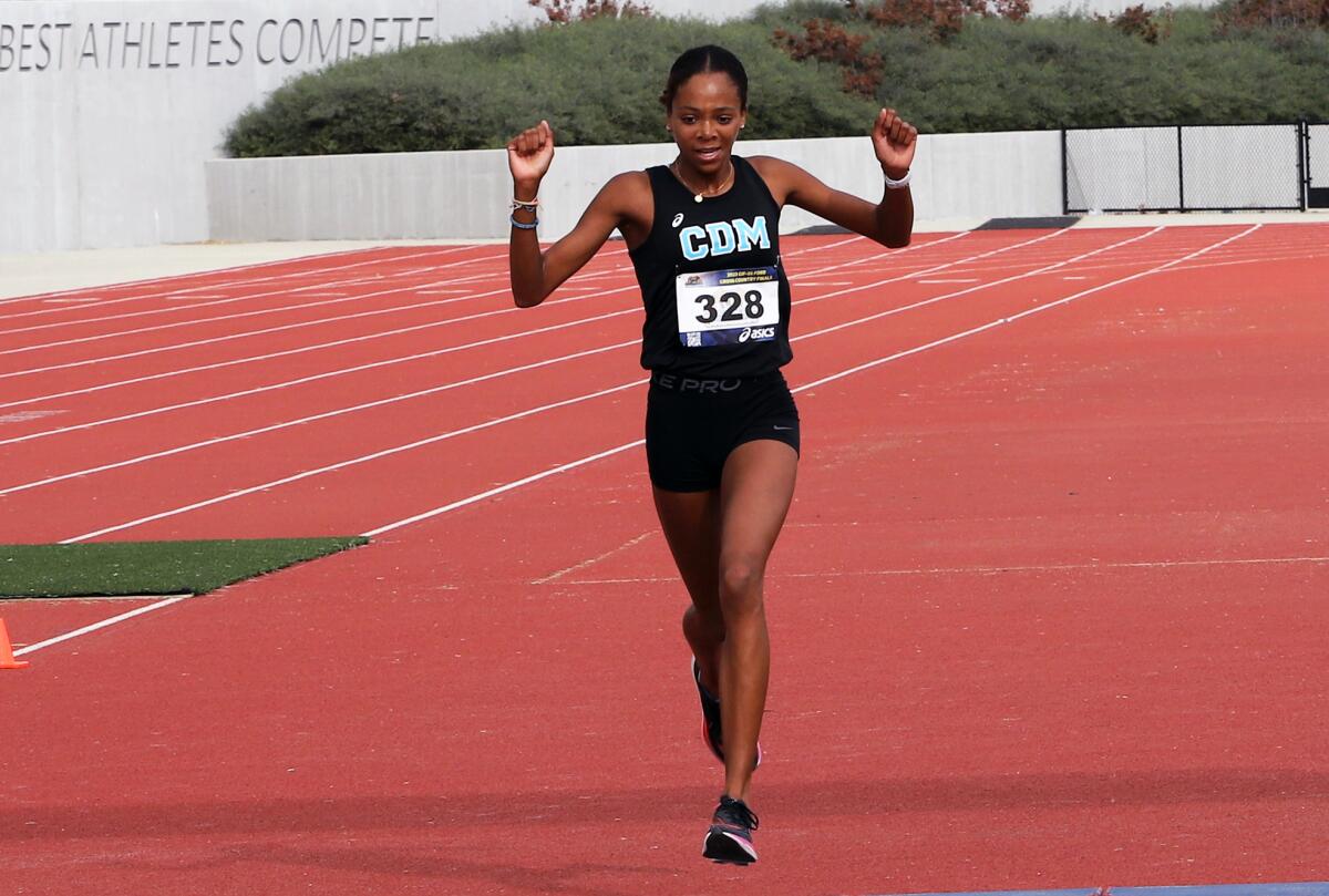 Corona del Mar's Melisse Djomby Enyawe (328) raises her arms in victory as she crosses the finish line on Saturday.