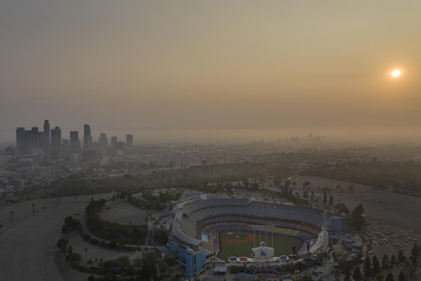 An aerial view of Dodger Stadium and the downtown Los Angeles skyline at sunset