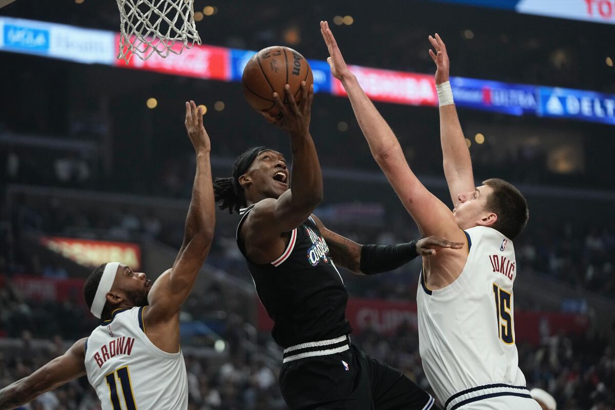 Clippers guard Terance Mann goes up for a shot as the Nuggets' Bruce Brown, left and Nikola Jokic defend Friday night.