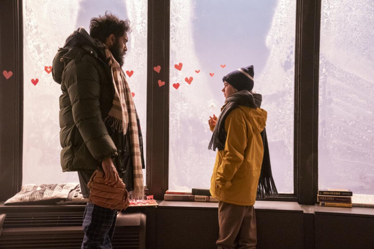 A man and a little girl stand before a frosted window with hearts on it